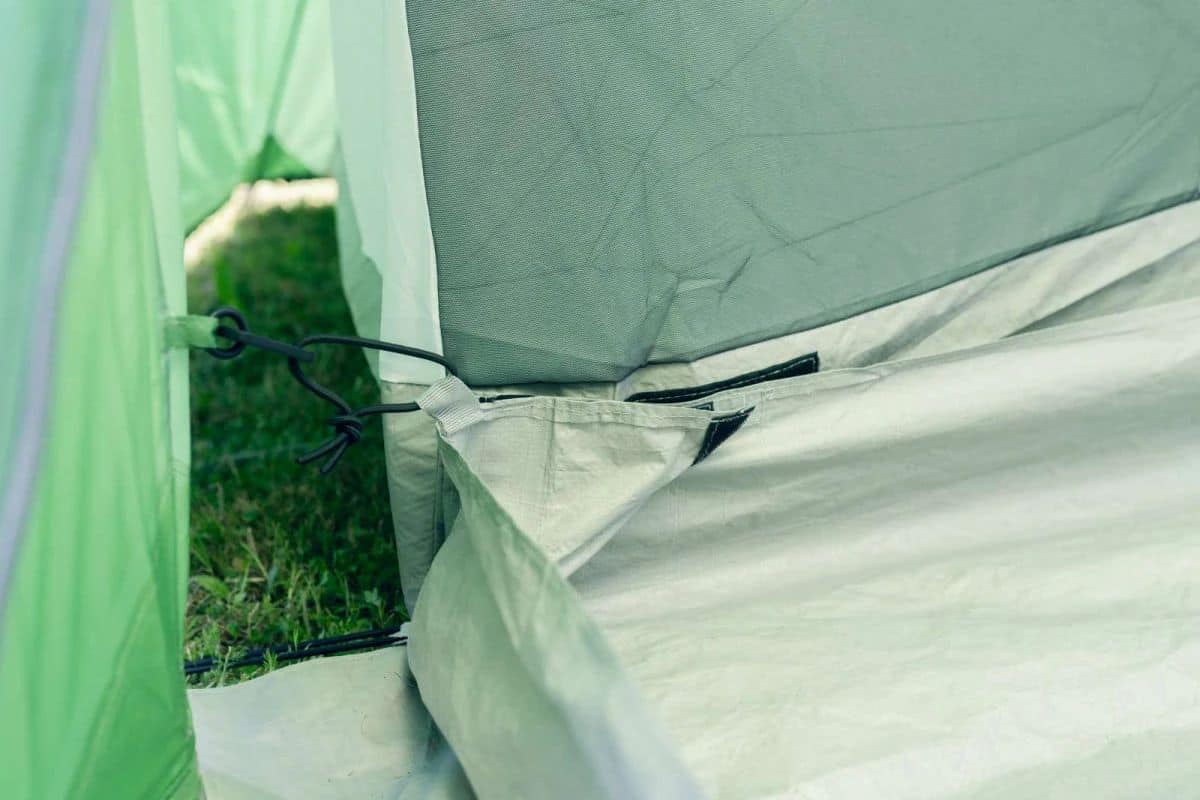 Алт текст: Тънка верига и шнур за закрепване на спортна палатка в outdoors setting.