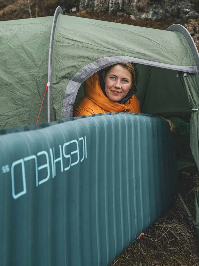 Палатка за къмпинг с жена вътре, на открито, сред природата, за къмпинг приключения.
