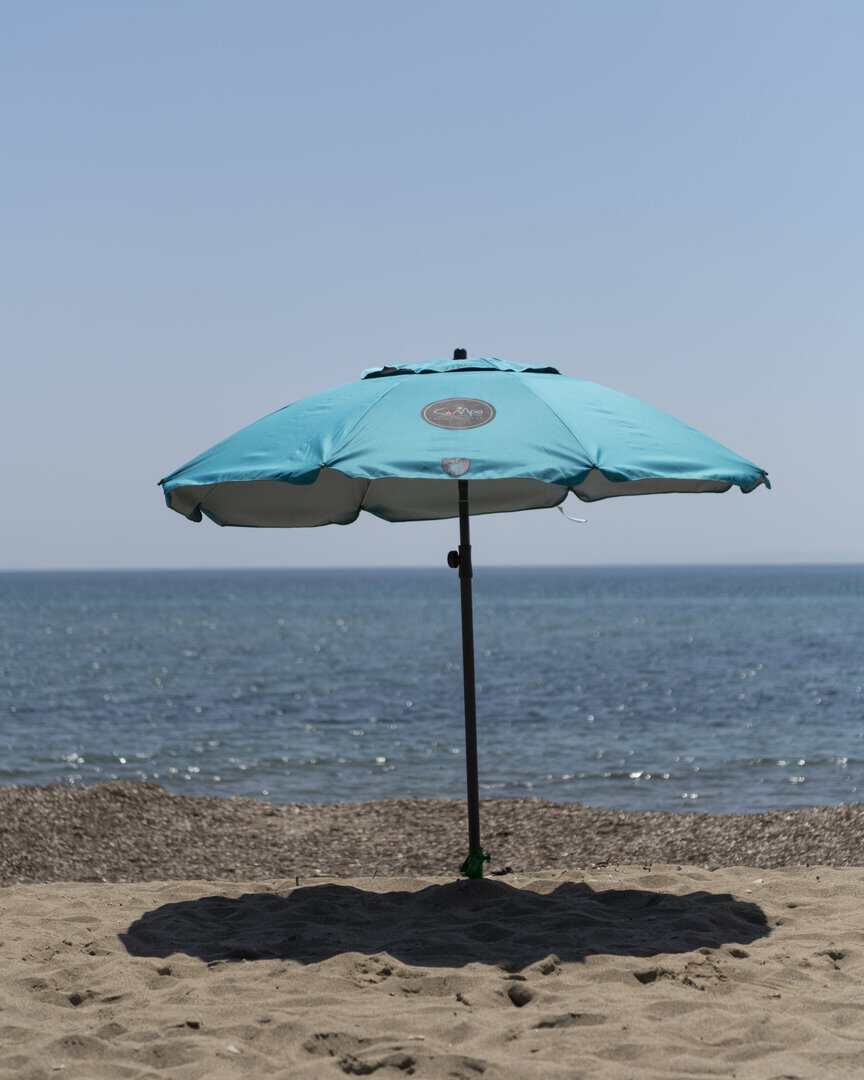 Плажен чадър на пясъка с изглед към морето.