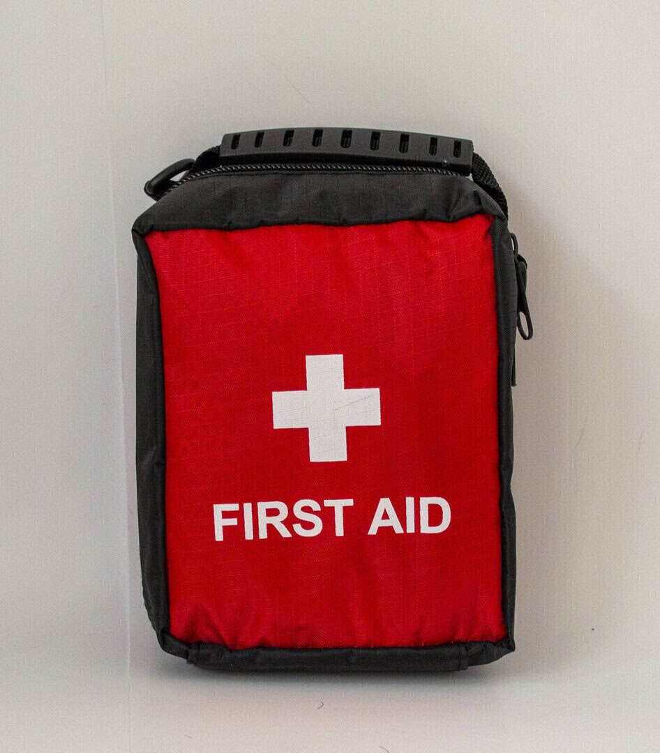 Червена аптечка за първа помощ с бяла кръст и надпис "FIRST AID".