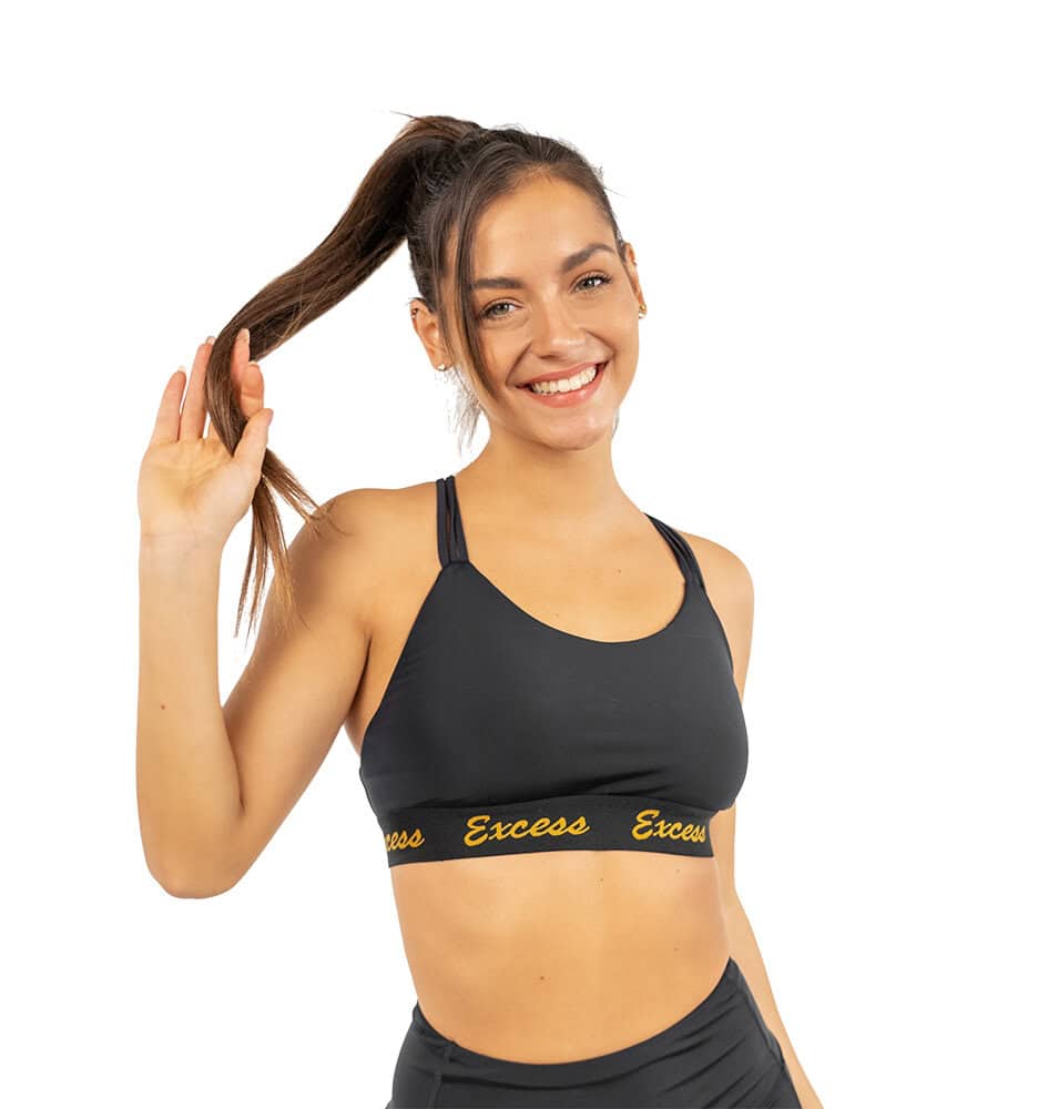 Млада жена носи спортен комплект Excess Black & Gold, усмихната и щастлива.
