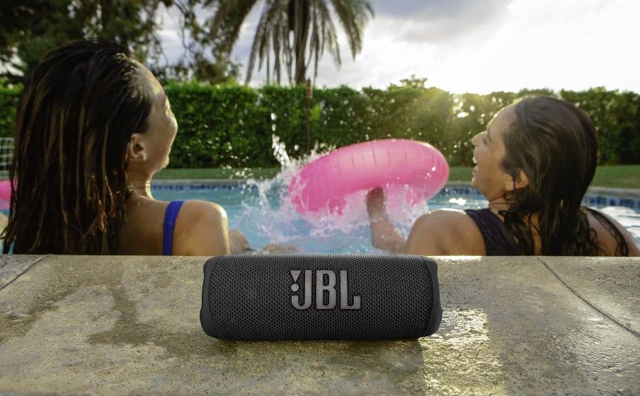 JBL Flip 6 Bluetooth колона на открито с две жени в басейн.